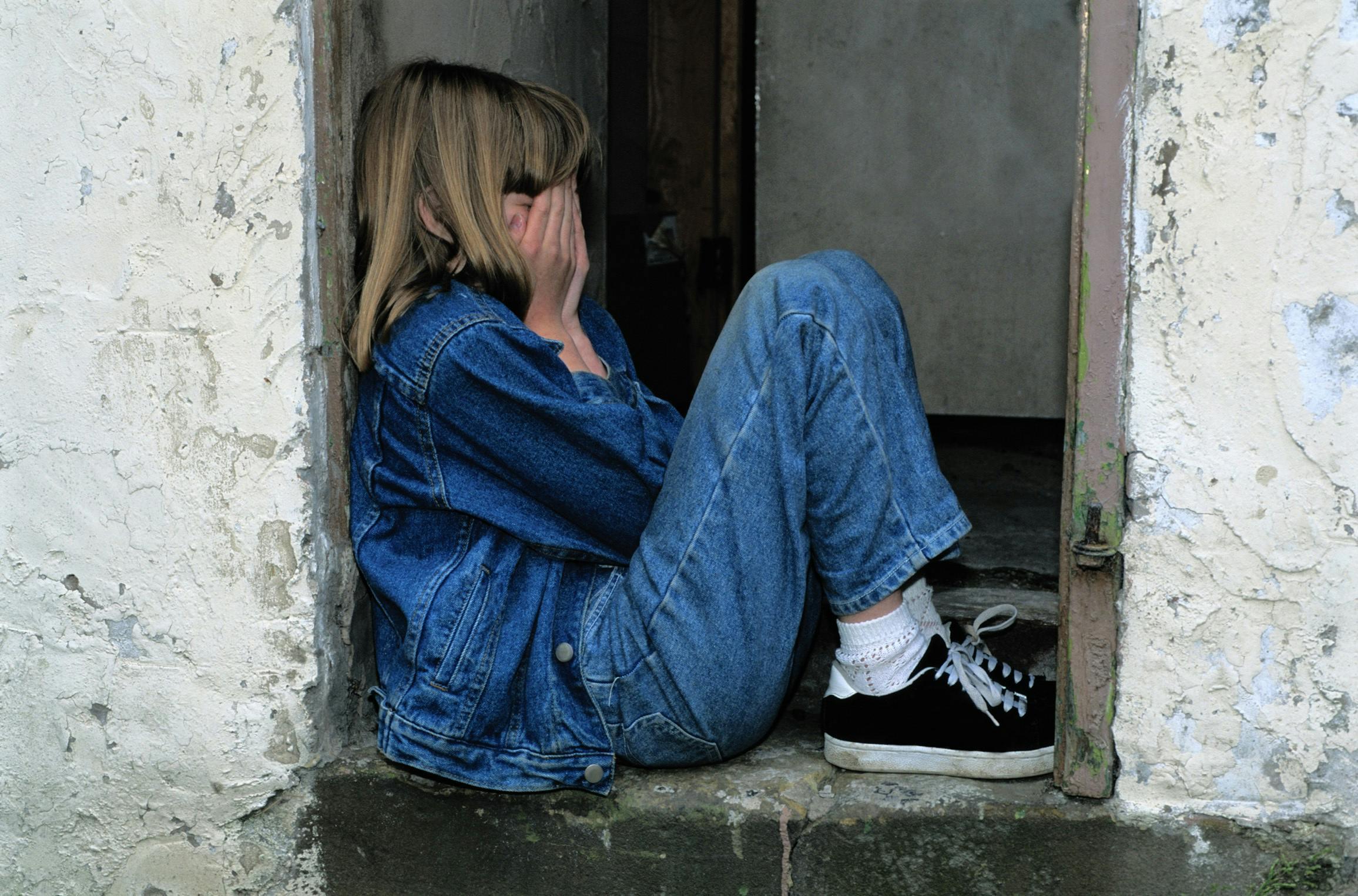 sad girl sitting in a wall crevice